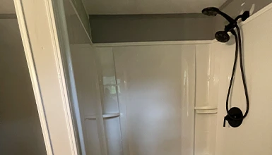 Modern white shower stall with black shower head and fixtures.