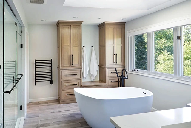 Modern bathroom with freestanding tub, custom cabinets, and heated towel rack.