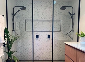Modern double shower with black fixtures and white patterned tile.