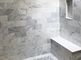 durable marble tile shower with built-in bench and decorative floor.