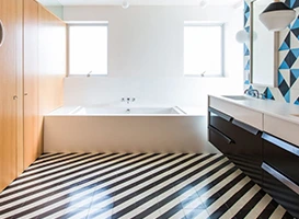 Modern bathroom with black and white striped tile floor and luxury bath.