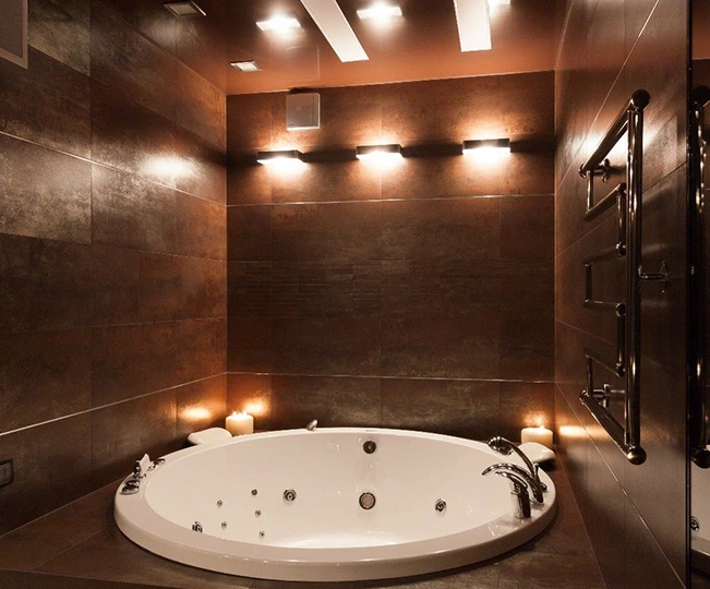 Modern bathroom with a luxurious white jacuzzi tub and warm lighting.