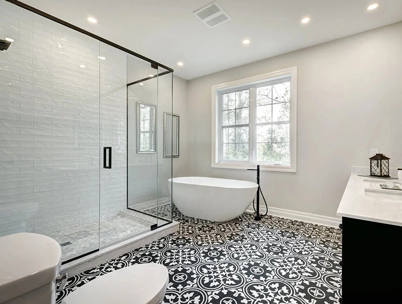 bathroom with black and white patterned floor, freestanding tub, and glass shower.