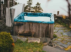 Rustic outdoor hot tub with wooden paneling and lush greenery