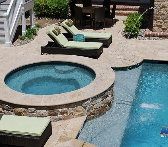 Luxury backyard with pool, spa, lounge chairs, and stone patio.
