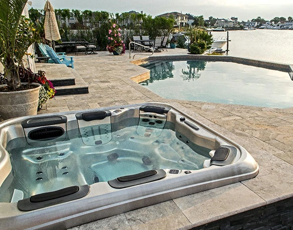 Luxury residential outdoor spa install on a patio next to a swimming pool and waterfront.