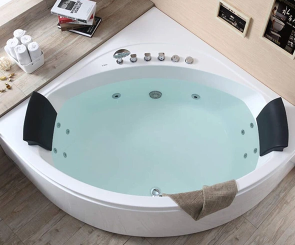 Corner whirlpool bathtub filled with water, featuring black headrests and chrome fixtures.