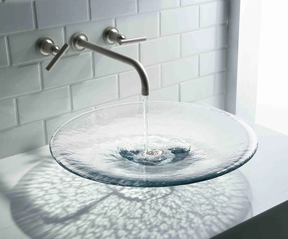 Modern bathroom: glass vessel sink with wall-mounted faucet.
