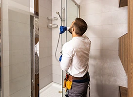 Plumber repairing a shower head in a modern bathroom. Shower repair service.