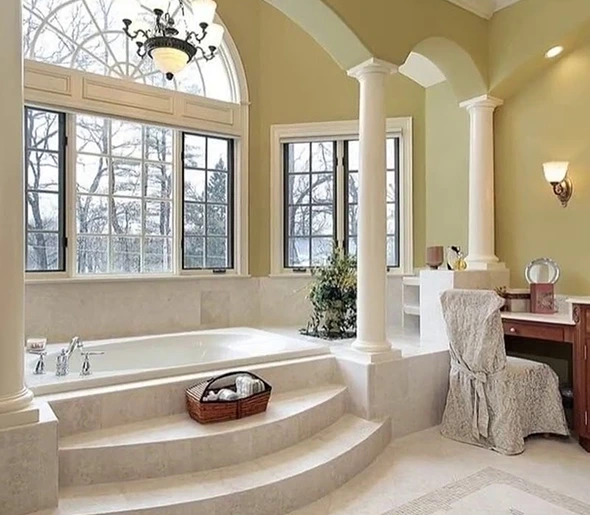 Spa-style bathroom design with a luxurious soaking tub, columns, and large windows.