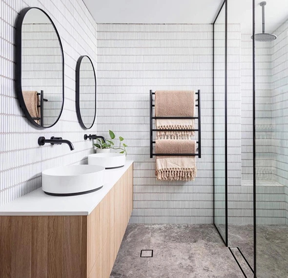 Modern bathroom with dual sinks, wood vanity, black fixtures, and a glass-enclosed shower.