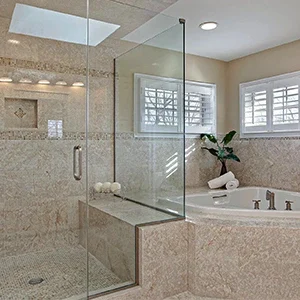 Luxurious bathroom with glass shower enclosure, beige marble tiles, and a soaking tub.