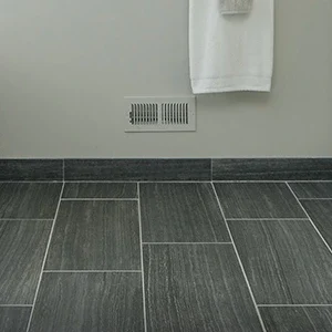 Gray kitchen tile floor with baseboard and wall vent, part of a kitchen remodel.